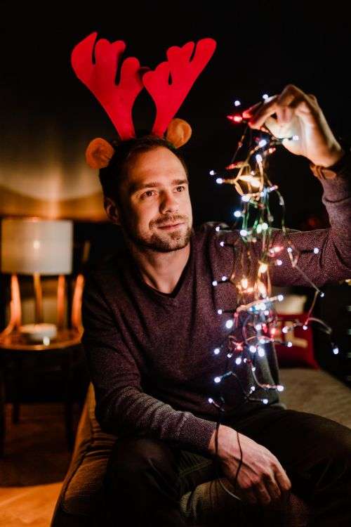 A handsome young man with Christmas tree lights