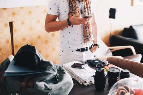 Man Checking His Phone while Packing for a Trip