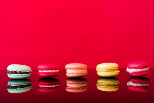 Colorful Yummy Macarons on Glossy Table and Red Background
