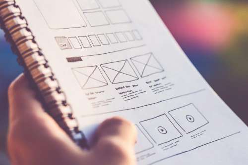 Designer Holding a Notebook with Web Site Wireframes Layout