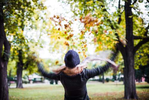 Girl Throwing Autumn Leaves in The Air