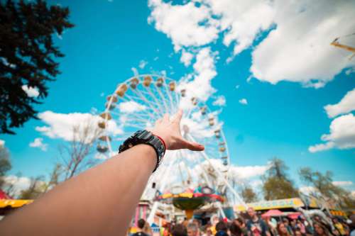 Hand Reaching the Ferris Wheel in Amusement Park