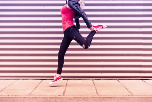 Young Happy Woman Jumping in Front of Metal Wall