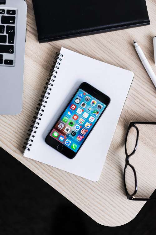 iPhone Lying on Notebook and Wooden Desk Mockup