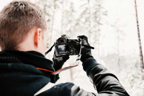 Photographer in Snowy Forest Taking Winter Photos