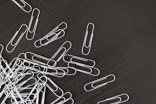 Pile of Silver Paper Clips on Black Desk