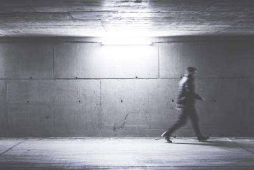Man Walking Through Concrete Underpass