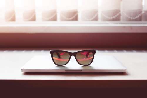 Sleek Sunglasses on Closed MacBook Laptop