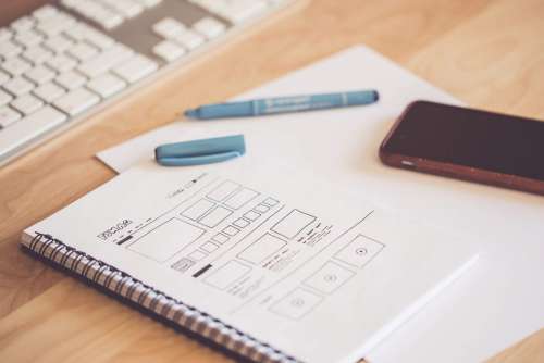 Web Designer Sketching a Wireframe Layout Ideas in a Notebook