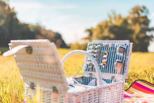 White Picnic Basket with Service on a Meadow