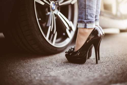 Woman in Black High Heels Standing Next to a Car