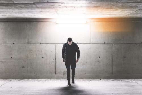 Young Man Walking in Conrete Underground Walkway