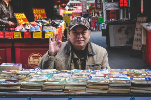 An old Chinese uncle selling tiny storybooks in the middle of the street, Tianjin, China.