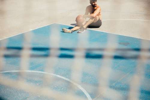 Man Sitting On Basketball Court Photo