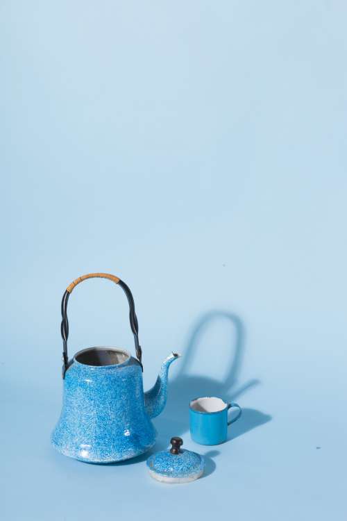 A Blue Kettle And Mug Against A Blue Background Photo
