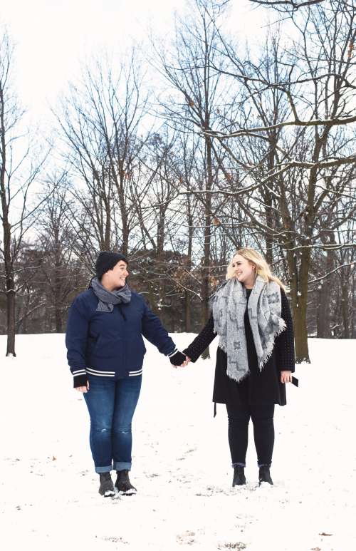 A Couple Hold Hands While Walking Through The Snow Photo