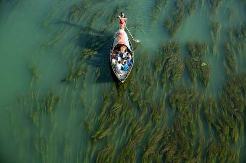 A Man Pushing A Small Boat Across Shallow Waters Photo