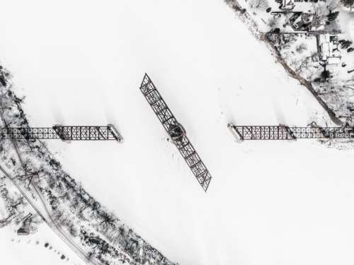 A Railway Swing Bridge On A Frozen River Covered In Snow Photo