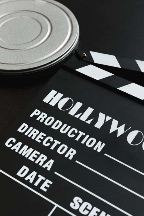 A Silver Film Reel Canister And A Movie Clapper Board Photo