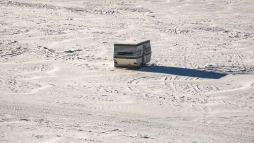An Abandoned Camper Trailer Parked In An Open snow-covered Field Photo