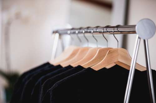 Black And Blue Clothing On A Rack In A Sunlit Shop Photo
