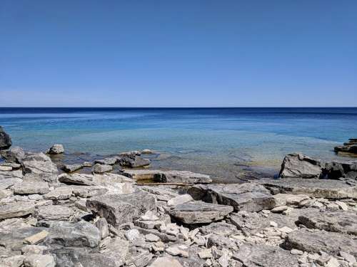 Blue Sky Clear Water And Rocky Shore Photo