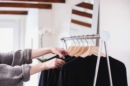 Comparing Black T-Shirts On A Clothing Rack In A Sun-Lit Shop Photo