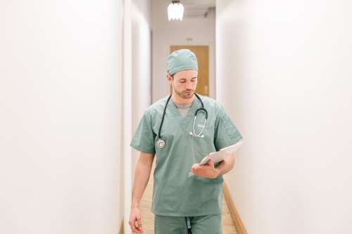 Doctor Walking Down Hallway With Clipboard Photo