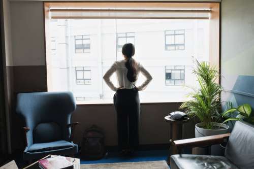 Female Executive Looks Out Modern Office Window Photo