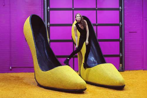 Female Model Perches Atop Giant Yellow High Heel Shoes Photo