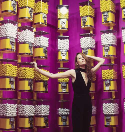 Female Model Poses In Front Of Gumball Machine Covered Walls Photo