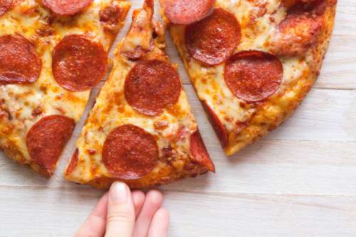 Hand Grabbing A Hot Slice Of Pizza Photo