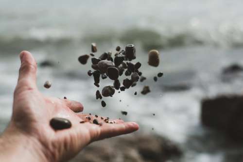 Hand Tossing Pebbles Photo
