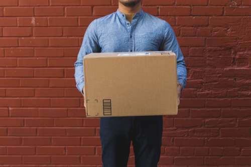 Man Holding Shipping Box On Red Brick Photo