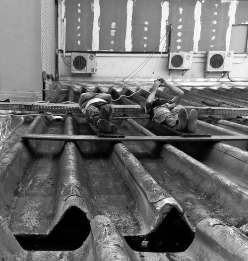 Men Laying On Metal Rooftop Photo