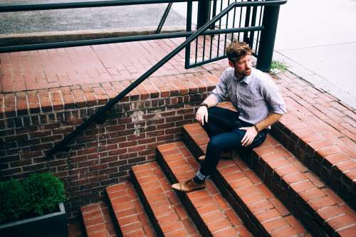 Men's Fashion Man In Shirt And Jeans Sat On Steps Photo
