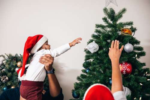 Parents Help Young Son Decorate Christmas Tree Photo