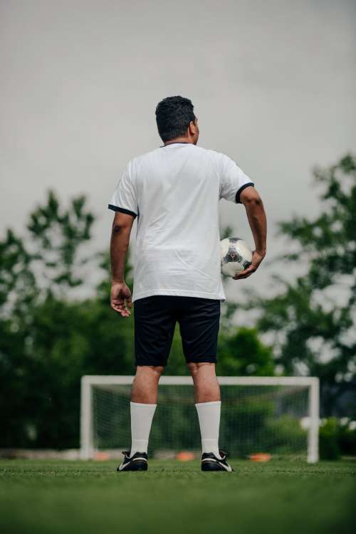 Portrait Of Soccer Player Holding Ball On Empty Field Photo