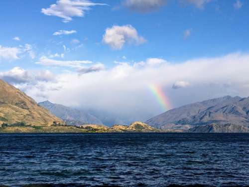 Rainbow Reaches For Clouds By Shore Photo
