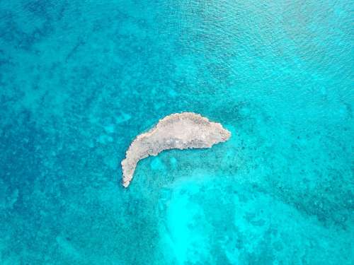 Small Rocky Island In Blue Ocean Shallows Photo
