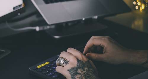 Tattooed hands Typing On Office Keyboard Photo