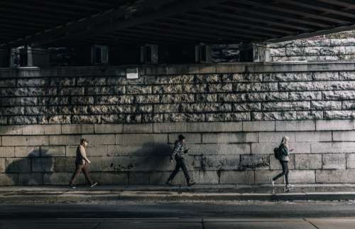 Three Urban Pedestrians Walk Under Bridge Photo