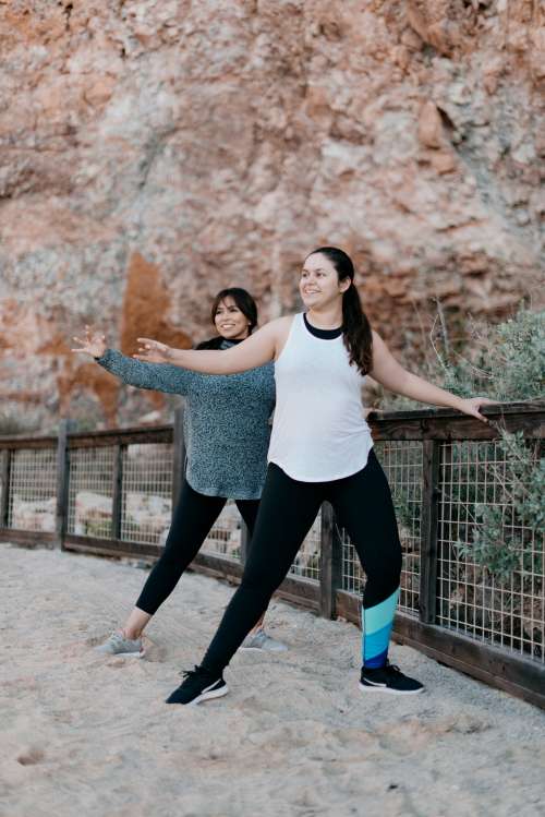 Two Women Strike A Yoga Pose On The Beach Photo