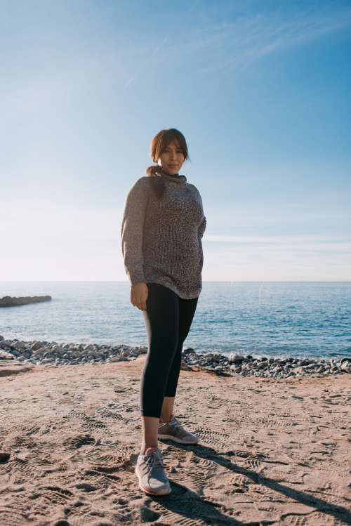 Woman In A Sweater Stands On A Beach In The Morning Photo