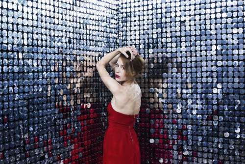 Woman In Red Dress Rests Elbows Against Wall Of Mirrors Photo