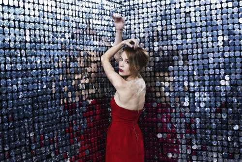 Woman In Red Dress Stretches Out Arms Against A Wall Of Mirrors Photo