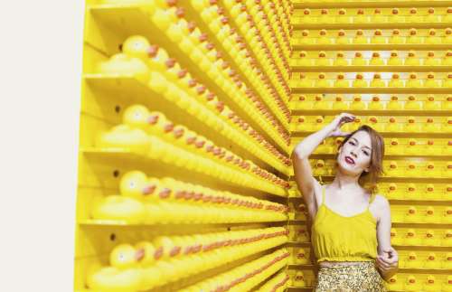 Woman In Yellow Stands Before A Wall Of Rubber Ducks Photo