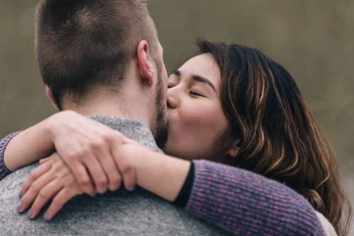 Woman Kisses Man With Her Arms Around His Neck Photo