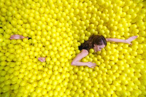 Woman Swimming Through Yellow Ball Pool Photo