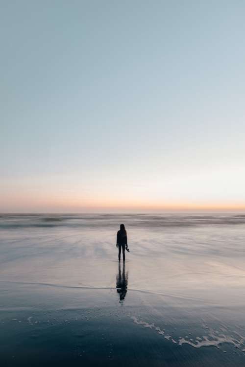 Woman Wades In Ocean At Sunset Photo